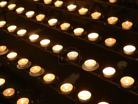 Photo for Votive candles with the flame by pilgrims during the religious service inside the church of god - Royalty Free Image