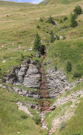 Foto de Cascada de agua de manantial que fluye entre las rocas de los Alpes europeos en verano - Imagen libre de derechos