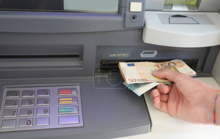 hand withdrawing euro banknotes in automatic teller machine in Europe