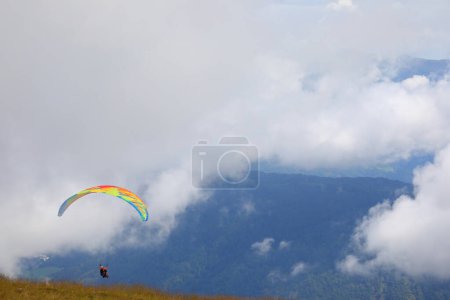 Foto de Parapente con dos personas a bordo para un vuelo de pareja y las nubes en las altas montañas - Imagen libre de derechos