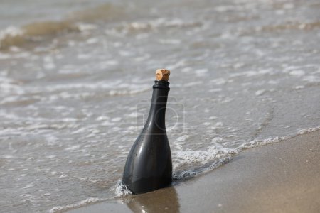 Photo for Dark Green Glass bottle on beach with a secret message inside - Royalty Free Image
