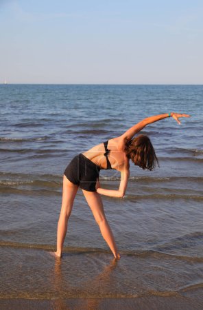Foto de Chica joven mare ejercicio físico en verano junto al mar - Imagen libre de derechos
