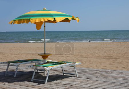 Photo for Yellow and green sunshade and deckchair in the beach in summer - Royalty Free Image