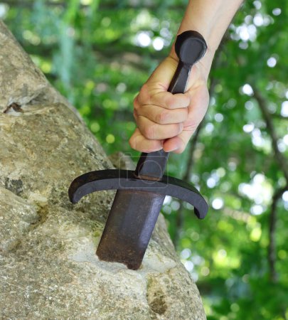 Foto de Mano fuerza extrae la espada en la roca como en la historia mitológica del rey Arturo - Imagen libre de derechos