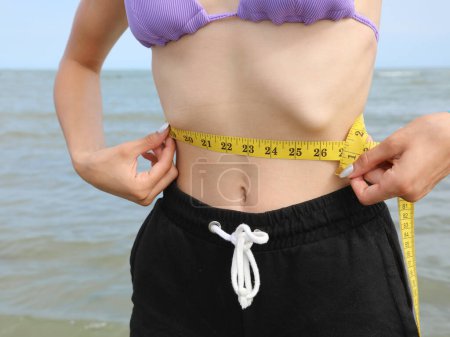 Photo for Skinny young girl with eating disorder measuring ther waistline - Royalty Free Image