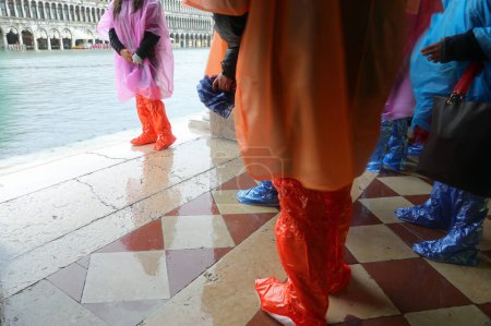 Photo for Many people with waterproof gaiters to protect their footwear during high tide on the island of Venice in Italy - Royalty Free Image