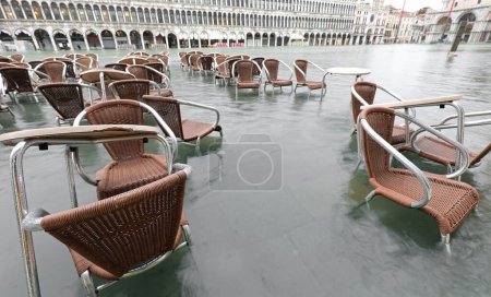Photo for Tables and chairs outdoor cafe in St. Mark square Venice ITALY during high tide completely flooded - Royalty Free Image
