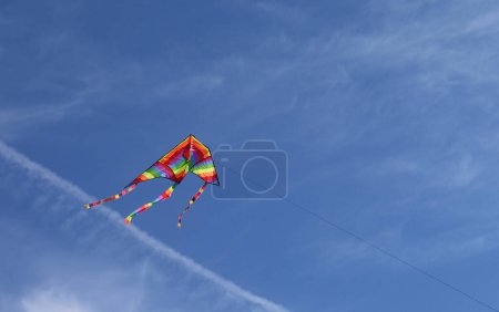 Foto de Cometa colorida de muchos colores de las moscas del arco iris atadas a un hilo en el símbolo del cielo de la infancia y el cuidado - Imagen libre de derechos
