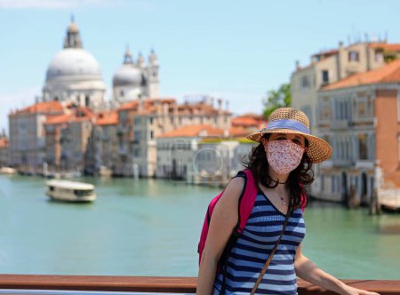 Photo for Beautiful young woman tourist with mask and straw hat visiting Venice during the lockdown in Italy - Royalty Free Image