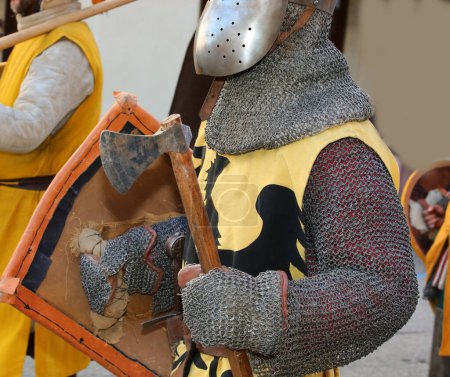 Foto de Caballero medieval con hacha de ataque y armadura y casco de metal protector en su cabeza durante una recreación histórica - Imagen libre de derechos