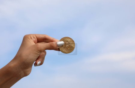 Téléchargez les photos : Main de fille tenant pièce d'or avec lettre majuscule B symbolisant crypto-monnaie Bitcoin - en image libre de droit