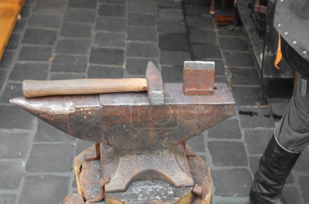 Photo for Very heavy anvil like the hammer in the blacksmith s shop of which we see a black boot - Royalty Free Image