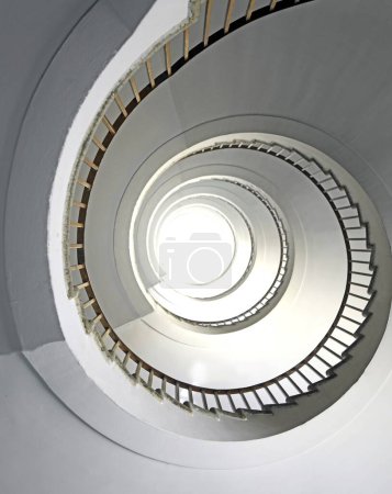 Téléchargez les photos : Escalier en colimaçon montant verticalement sans personne avec balustrade en fer et lumière blanche au sommet - en image libre de droit