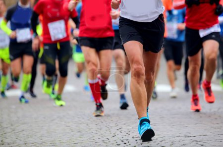 Photo for Legs of many people running during the marathon in the city streets - Royalty Free Image