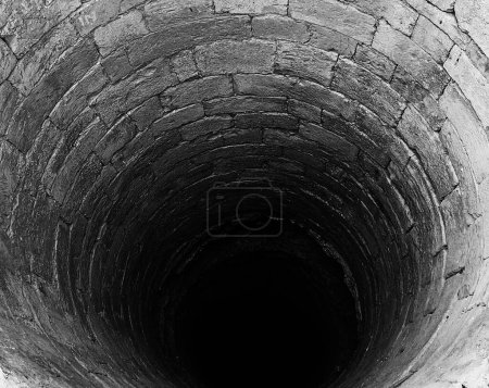 Photo for Narrow tunnel or a bottomless pit made of rocks and stones in black and white - Royalty Free Image