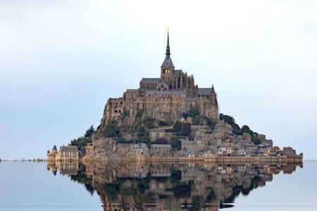 Photo for Reflected on the water at high tide of the Hill with the abbey of Mont Saint Michel in Normandy in Northern France - Royalty Free Image