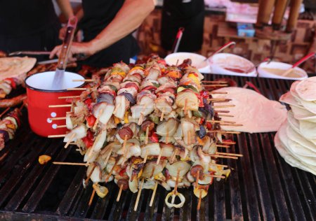 Foto de Muchos pinchos con carne y verduras cocidas para la venta en el puesto de comida de la calle en el mercado de la ciudad - Imagen libre de derechos