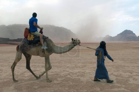 Photo for Camel driver leading a tourist for desert visit on the big camel - Royalty Free Image