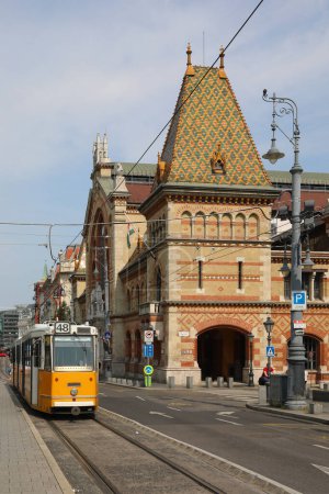 Photo for Budapest, B, Hungary - August 19, 2023: Ancient Palace of Covered market called nagyvasarcsarnok and yellow tram - Royalty Free Image