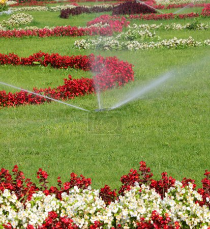Téléchargez les photos : Système d'irrigation automatique du jardin de fleurs avec des parterres bien entretenus avec des fleurs - en image libre de droit