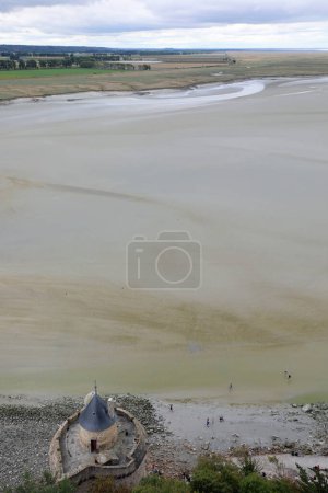 Photo for Elevated panoramic view from Mont Saint Michel Abbey in Normandy in France and people walking on the sand at low tide - Royalty Free Image