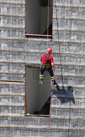 Foto de Bombero valiente en arnés trepando sobre un edificio destruido - Imagen libre de derechos