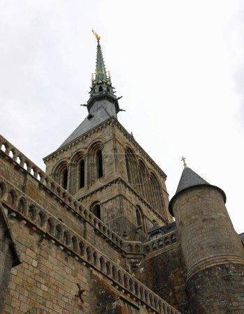 Foto de Vista desde abajo del campanario con la estatua de oro del arcángel Miguel en la Abadía del Mont Saint Michel en Francia - Imagen libre de derechos