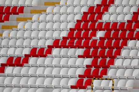 Foto de Muchos vacíos asientos de plástico rojo y blanco en el estadio se encuentra sin personas antes del evento deportivo - Imagen libre de derechos