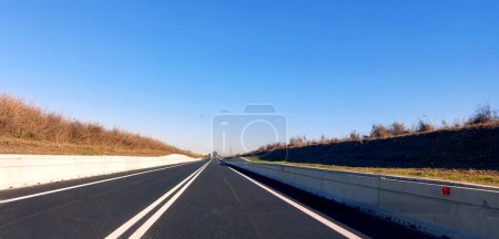 Téléchargez les photos : Grande route nouvellement asphaltée avec double ligne continue ce qui signifie que le dépassement est interdit - en image libre de droit