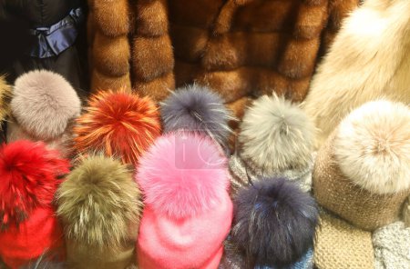 many colorful fashionable hats and caps with fur fur for sale in the window of winter clothing boutique