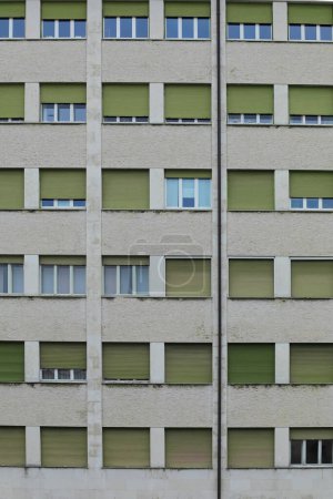 Téléchargez les photos : Façade d'un bâtiment anonyme dans un quartier ouvrier avec des fenêtres avec des volets fermés et d'autres ouverts sans personne - en image libre de droit