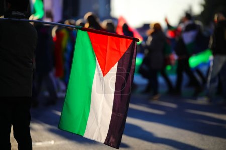 Photo for Palestinian flag waving during a peaceful protest demonstration with many people in the streets of the city - Royalty Free Image