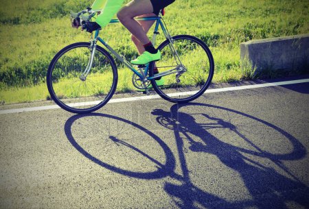 Téléchargez les photos : Ombre du cycliste sur le vélo de course sur la route en contre-jour avec un effet antique idéal comme arrière-plan pour un concept sportif - en image libre de droit