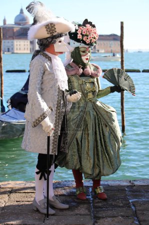 Foto de Venecia, VE, Italia - 13 de febrero de 2024: pareja de amantes enmascarados con ropa muy elegante y lujosa durante el carnaval veneciano - Imagen libre de derechos