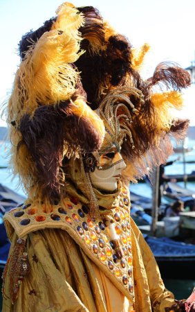 Photo for Venice, VE, Italy - February 13, 2024: masked person with huge headdress with feathers and decorations and handmade dress during the Venetian carnival - Royalty Free Image