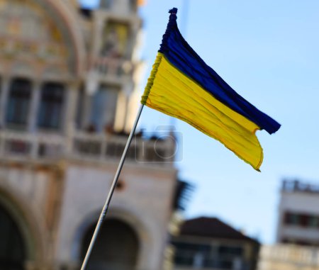 small flag of Ukraine flying in a city during the demonstration without people