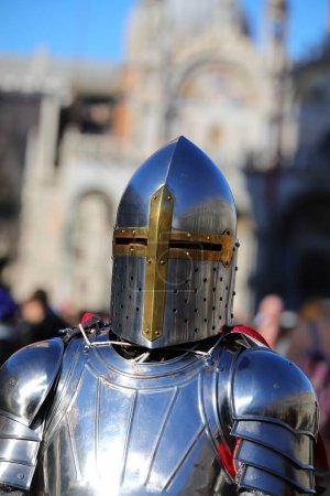 Photo for Knight with steel armor and large helmet to protect his head and ancient palace in background - Royalty Free Image