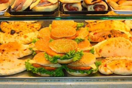 Foto de Sándwiches de hamburguesas con chuleta y piadina y otros alimentos callejeros en la ventana del bar - Imagen libre de derechos