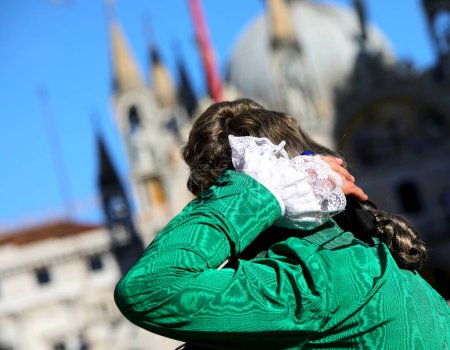 green dress of masked nobleman with wig during the Venice Carnival celebrations in saint mark square