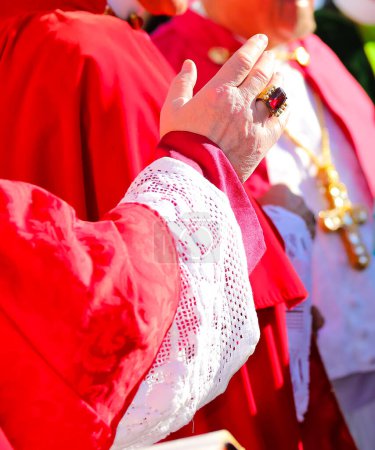 Téléchargez les photos : Main du prêtre avec soutane rouge lors de la bénédiction des fidèles à la fin de la messe solennelle - en image libre de droit