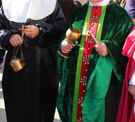 priest with cassock and aspergillum while performing the blessing with holy water and incense during the holy mass