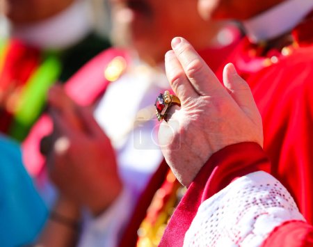 Hand mit Rubinring des in Rot gekleideten Kardinals bei der Segnung der Gläubigen