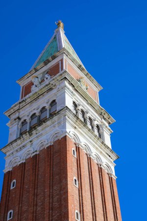 detail of the tip of the bell tower of Saint Mark in the famous square of Venice in Italy with blue sky