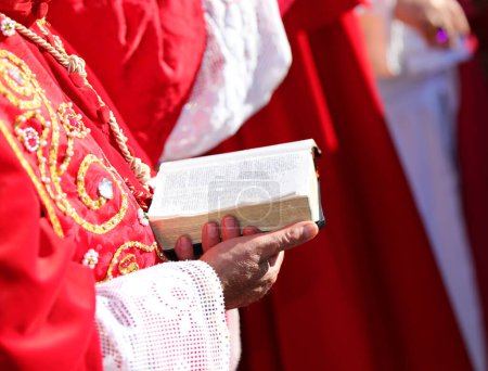 Foto de Mano del cardenal leyendo el libro de la Biblia con las sagradas escrituras durante la misa solemne - Imagen libre de derechos