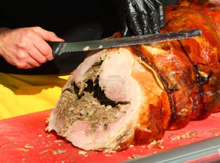 Hand in einem Handschuh Scheiben Porchetta eine würzige italienische Schweinefleisch Salume