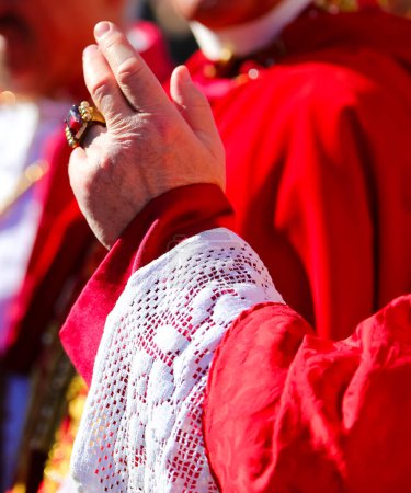 hand of the cardinal with red cassock during the blessing of the faithful at the end of the solemn mass