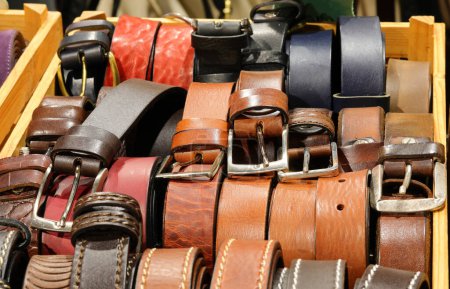 Leather belts handcrafted by artisans with metal buckles are available for purchase at the leather goods store