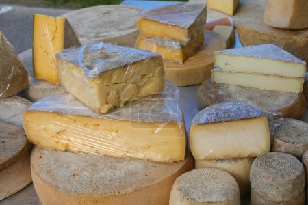 meules de fromage vieilli et morceaux de fromage frais à vendre dans un étal de marché