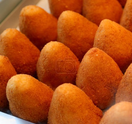 Many fried food called arancini ora ARANCINE in italian language filled with rice vegetables meat or cheese on sale at a market stall in Sicily southern Italy