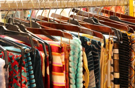Foto de Ropa y telas en perchas dispuestas en una tienda que vende ropa y telas finas de alta costura artesanal - Imagen libre de derechos